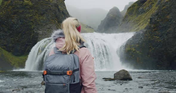 Iceland Woman with Backpack Enjoying Stjornarfoss Waterfall Near Kirkjubaejarklaustur