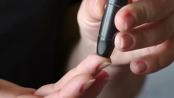 Girl Checks the Blood Sugar Level with a Lancet