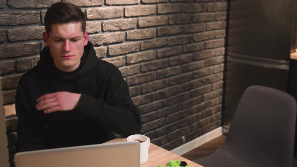 Handsome Caucasian Young Man Coughing While Working on Laptop at Home Office