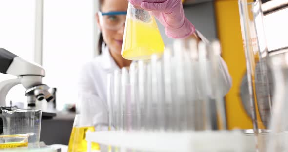 Scientist Stirs Yellow Oily Liquid in Flask in Laboratory Closeup