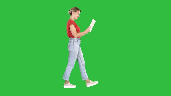 Happy woman walking with tablet on a Green Screen, Chroma Key.