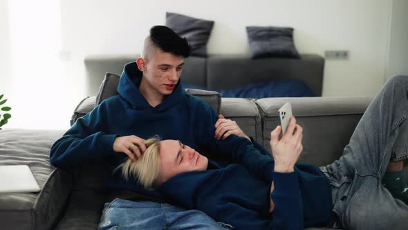 Happy Men Homosexual Couple Sit on Sofa and Using Smartphone Talking