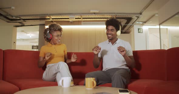 African American Woman and Man on a Sofa Dancing While Listening to Music