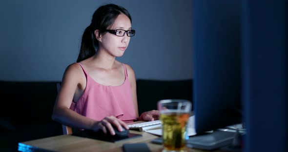 Woman using desktop computer at night
