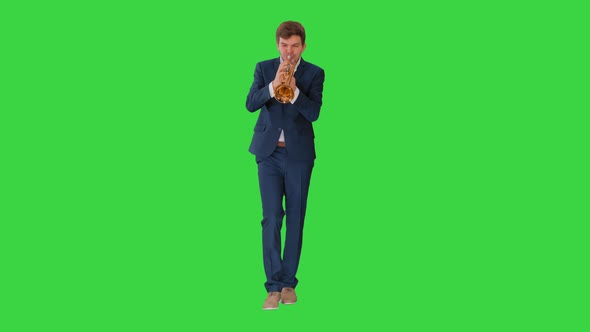 Young Man in Suit Playing a Trumpet While Walking on a Green Screen, Chroma Key.