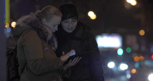 Women Friends Using Tablet PC When Waiting for Bus in the Street