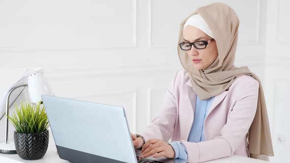 Woman in Hijab and Glasses Is Making a Boring Work on Her Laptop