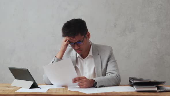 Tired Indian businessman working with paper document and goes to bed on the table