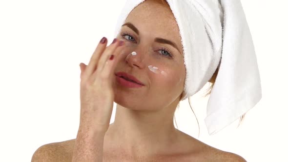Beautiful Young Woman Applying Cream on Face. Close Up, Bathroom