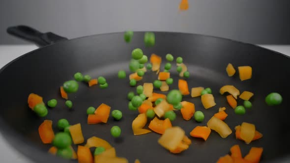 Colorful Vegetable Mix with Green Peas and Chopped Bell Pepper Falls in Slow Motion To the Hot Pan