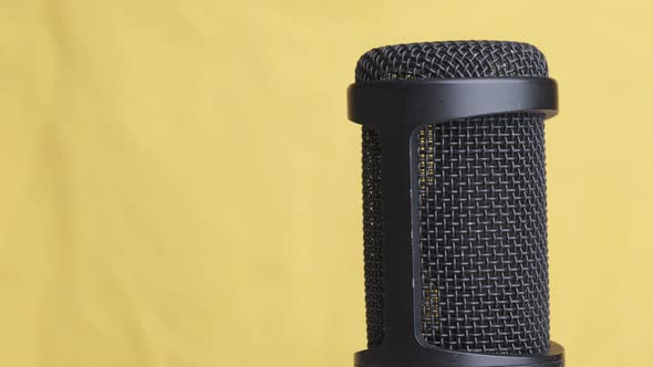 Studio Condenser Microphone Rotates on Yellow Background with Place for Text