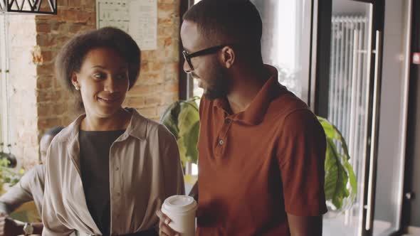 Afro-American Man and Woman Walking through Cafe and Chatting