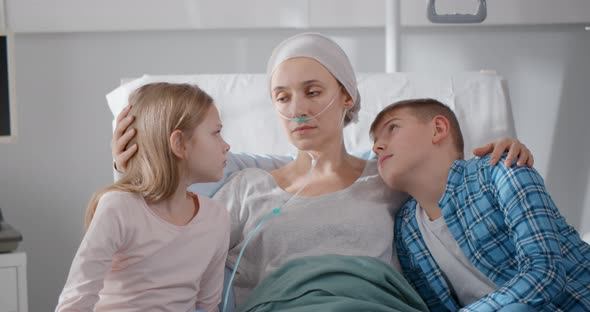 Unhappy Children Sitting with Sick Mother in Hospital Ward