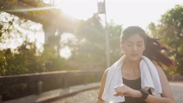 Happy Asian woman running in park on public green background,