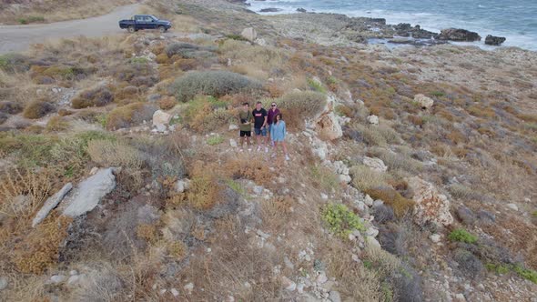 Friends travel concept. Four young tourists stand along rocky coastline in the countryside