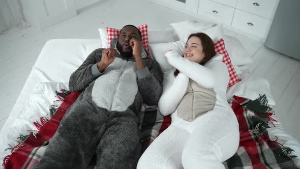 Positive Couple in Pajamas Dancing Lying on Bed