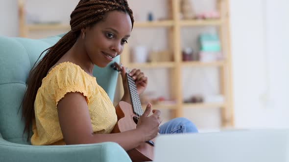 Woman Learning to Play Chords on Acoustic Guitar Ukulele and Watching Online Video Tutorial Spbi