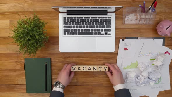 On Office Table is Put the Word Vacancy Collected By Hands of Wooden Cubes with Letters