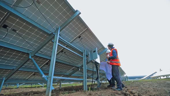 Solar power plant with two engineers. Two engineers examining solar power plant