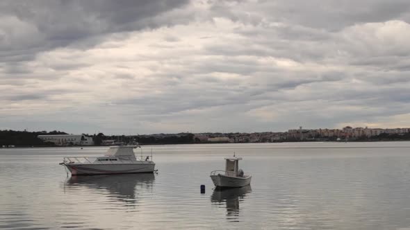 Two Boats Moored On Calm River In Seixal, Portugal On A Cloudy Day - wide shot