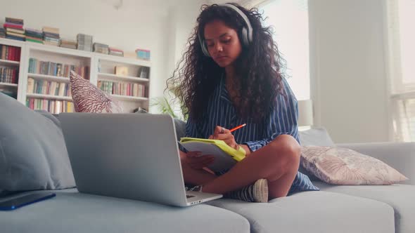 Focused Indian Teen Girl Making Notes While Listening to Online Lecture