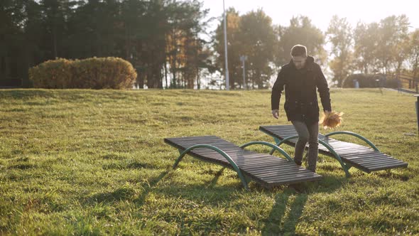 Man in Jacket with Yellow Leaves Lies Down on Sun Lounger Relaxing