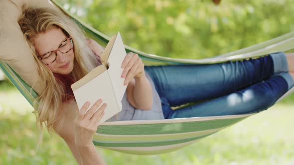 Smiling blonde woman with eyeglasses reading a book