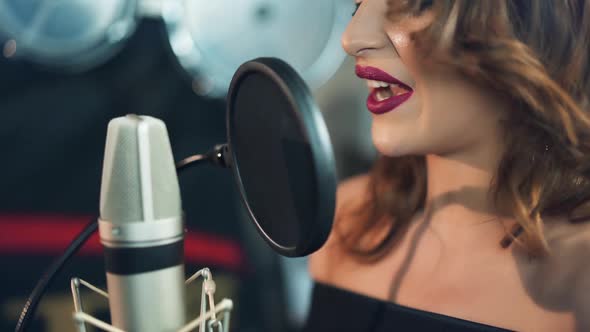 Woman singing in the recording studio. Profile of a woman with a beautiful face and lips.
