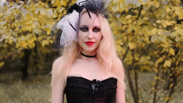 A beautiful girl in the image of a witch with black eyes and red lips. She looks into the frame and