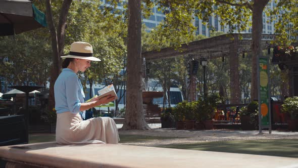 Young woman with a travel book in the park