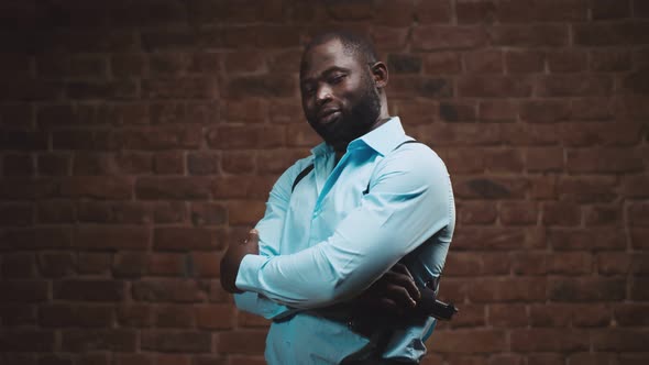 Portrait of African Police Officer with Handgun Posing at Camera with Arms Crossed