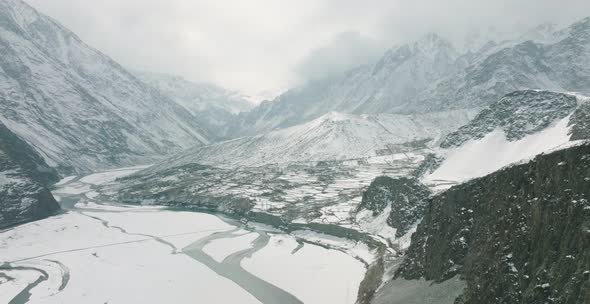 Aerial Cinematic View Of Snow Covered Hussaini Village In Hunza Valley Beside Frozen River. Dolly Ri