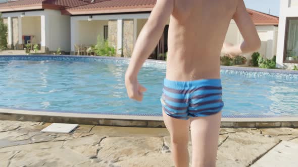 Back View Happy Boy Running and Jumping in Swimming Pool Child Having Fun Splashing Water