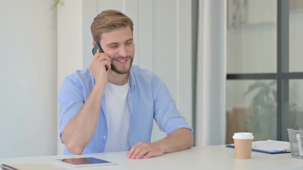Young Creative Man Talking on Smartphone in Office