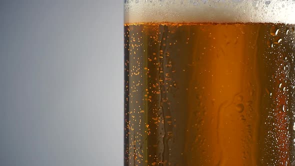 Cold Beer in a Glass Bottle with Dripping Condensation Drops and Air Bubbles