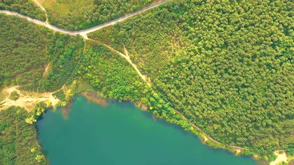 Aerial view of wild forest lake in summer. Small blue lake in green pine tree forest in rural