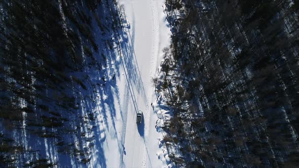 Aerial View of Car Moving on White Countryside Road in Winter Day.