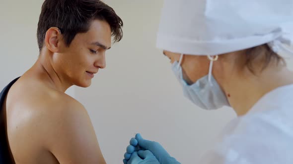 A Nurse Injects a Vaccine Against the Virus Into a Young Boy's Shoulder. Injection Intramuscularly.