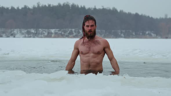 Muscular Man Showing Biceps in Ice Hole in Winter