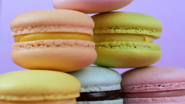 Multicolor Macarons, French macaroon, sweet tasty desserts. Isolated on a lilac background.