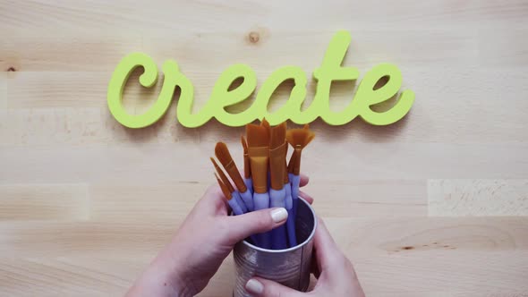 Green create sign with paint brushes on the table.