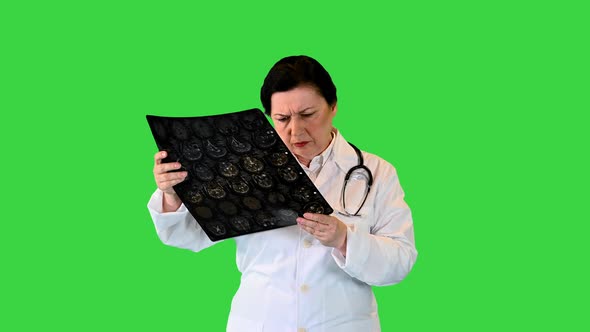 Mature Woman Doctor Reading MRI Film Scans While Walking on a Green Screen, Chroma Key
