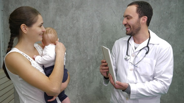 Cute baby boy and her mother consulting with the doctor