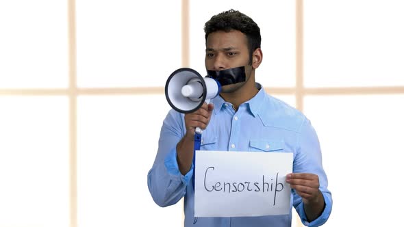 Young Businessman with Taped Mouth Holding Loudspeaker