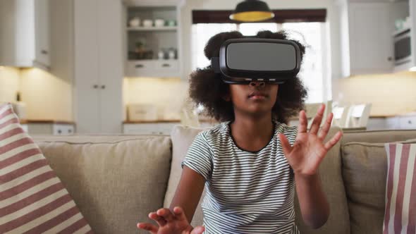 African american girl sitting on couch wearing vr headset