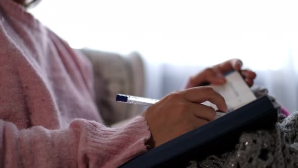 Unrecognizable Woman in Warm Knitted Sweater Writes Down Plans or Tasks for the New Year