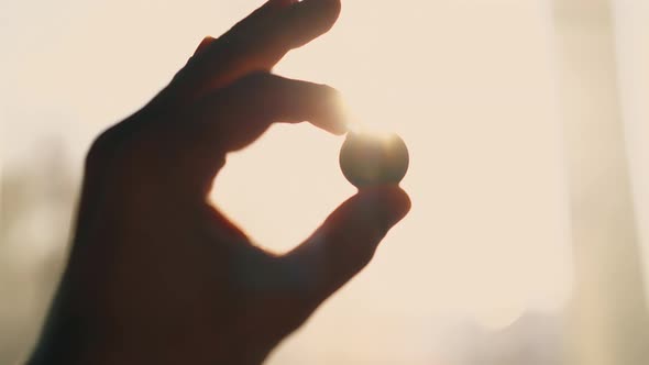 Silhouette of Man Hand with Coin at Backlight Close View