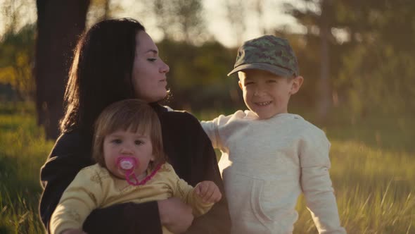 Mom Plays with Children in the Park on the Grass