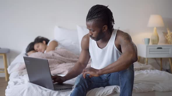 Confident Handsome Concentrated African American Man Typing on Laptop Keyboard with Young Beautiful