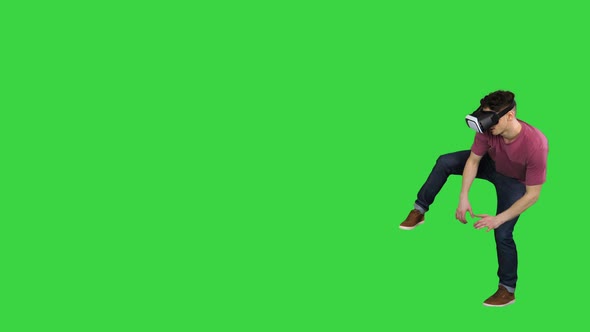 Man in Virtual Reality Glasses Wading Through Dangerous Virtual World on a Green Screen, Chroma Key.